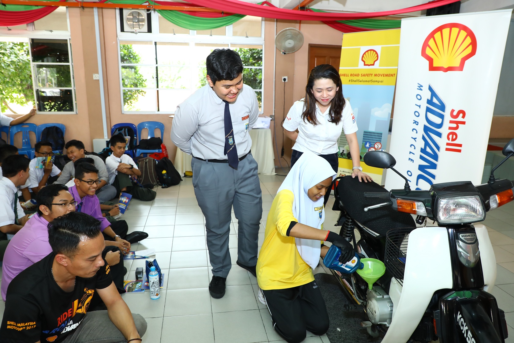 Shell Lubricants Mktg GM May Tan (R) watches as students learn how to ch...